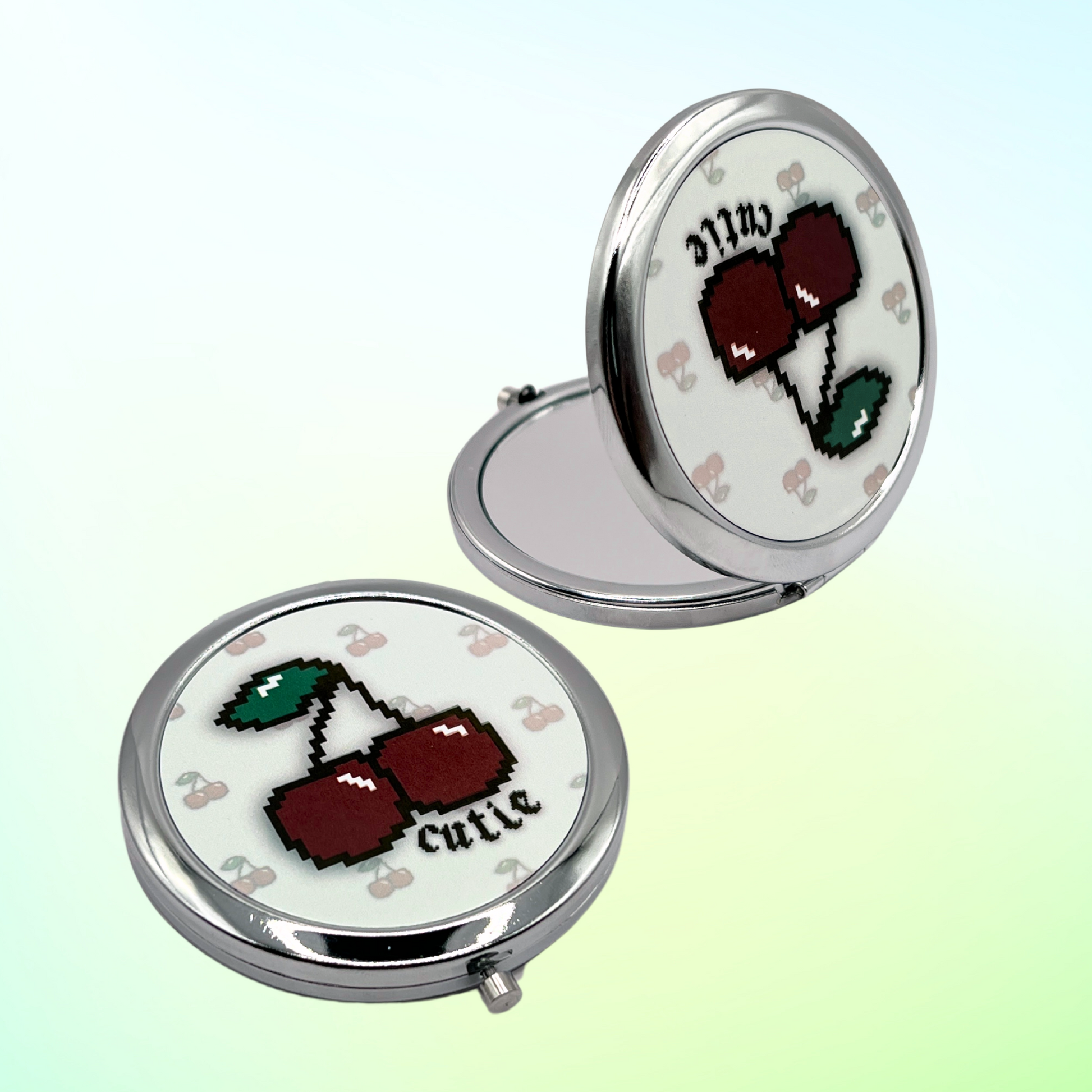 two compact mirrors with pixelated cherry design on a gradient background